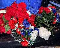 Group of artificial red poinsettias, red and white carnations, blue hydrangea-style flowers on wire stems
