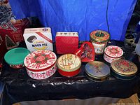 Front view of nine assorted metal cookie tins displayed on table