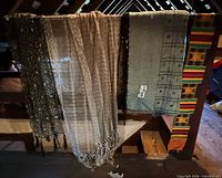 Four scarves hanging: patterned black/white, beige open weave, grey mirror-work, multicolour kente-style