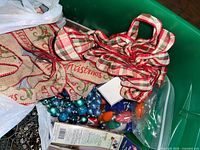Green tote holding ribbon bows, ornaments, bulbs