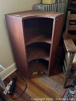 Full view of brown laminated wood corner cabinet showing three shelves