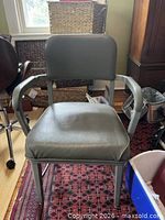 Front view of gray metal armchair showing seat, arms, legs