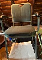 Front view of green cloth office chair with metal frame and armrests