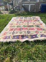 Full view of kilim rug laid flat on grass