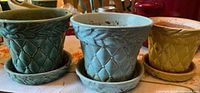 Front view of three McCoy quilted planters with saucers in teal, blue and yellow glazes