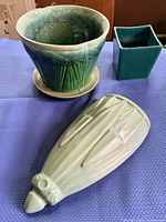 Round two-tone green planter, teal square planter, light celadon ribbed wall pocket on blue cloth