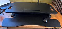 Top view of standing desk converter showing black laminate surface with integrated slot and carry handles