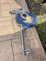 Full kit showing metal bar with pulley brackets, blue wire coil, tan rope coil and green cord