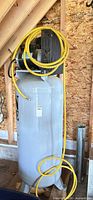 Full view of vertical air compressor with yellow hose
