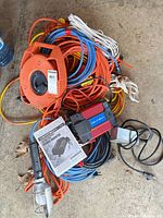 Lot overview showing power inverter, cord reel, work light, manual and multiple extension cords