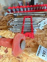 Group shot showing sockets on rail, combination wrenches on holder, red-handled scraper
