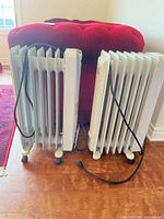 Both NOMA oil-filled radiator heaters front view showing fins, cords, casters