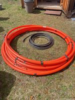 Large orange conduit coil and smaller black conduit coil on ground