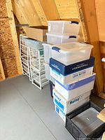 Side view of stacked plastic totes, wire drawer racks, copy-paper boxes and milk crate