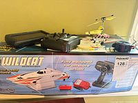 Lot overview showing helicopter, transmitters, chargers atop Aquacraft Wildcat box