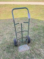 Full view of steel hand truck dolly on grass showing frame, wheels, toe plate