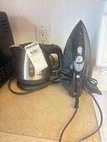 T-fal kettle on base beside Proctor Silex steam iron