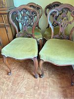 Four carved wood dining chairs showing overall design and condition