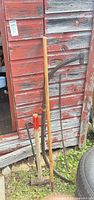 Group of four vintage hand tools leaning against shed
