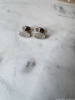 pair of oval sterling cufflinks on marble surface