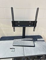 Full view of black metal swivel TV stand with hardware laid out on table