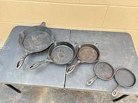 Top view of five cast iron skillets nested on table
