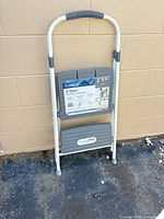 Step stool folded against wall showing label and overall condition