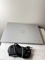 Closed silver HP Chromebook top view with charger