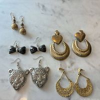 All five pairs of earrings displayed on marble surface