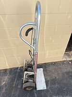 Side view of McLane aluminum appliance dolly showing frame, wheels, folding toe plate