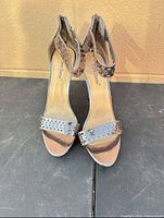 Front view of the pair of metallic perforated ankle-strap high heel sandals