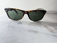 Front view of Ray-Ban tortoise shell frame sunglasses with green lenses on surface