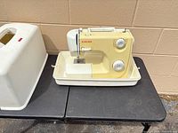 Front view of Singer 8280 sewing machine seated in plastic base with case lid to the side