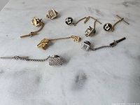 All eight men’s accessories laid out on white marble surface