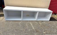 Front view of white laminate TV stand showing three cubbies