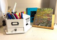 Desk organizer filled with pens, book stand with sketchbook and notebook