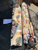 Umbrella folded inside matching carry bag, pole sections and paperwork visible on patio table
