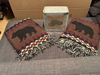 Two folded bear motif throws and sealed Pure Beech sheet set on sofa