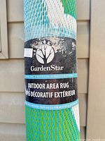 Close-up of GardenStar label on rolled rug showing brand and outdoor area rug text