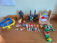 All items laid out on tabletop: tambourine, walkie-talkies, action figures, bookend, Tsum Tsum minis, animal figures, green vehicle, holiday items