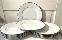 Stack of twelve white plates with platinum rims, front plate displayed upright