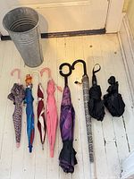 Full view of eight umbrellas laid out beside galvanized stand