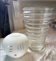 White spherical vase and clear ribbed cylindrical vase side by side