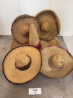 All six straw sombreros arranged together showing trims and bands