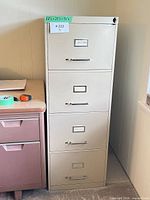Full view of beige metal 4-drawer filing cabinet beside desk