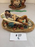 Front angled view of entire Naturecraft “Siesta” figurine showing reclining man, tub, boots, bottle and base details