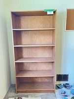Full front view of oak-veneered bookcase showing five shelves