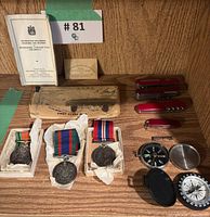 Overall view showing medals, mounting bar, Swiss Army knives, compass, booklet, and envelopes