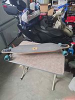 Full longboard on table, showing deck, trucks, wheels