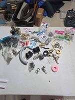 Overall table view showing assorted brass fittings, clamps, tape and tubing